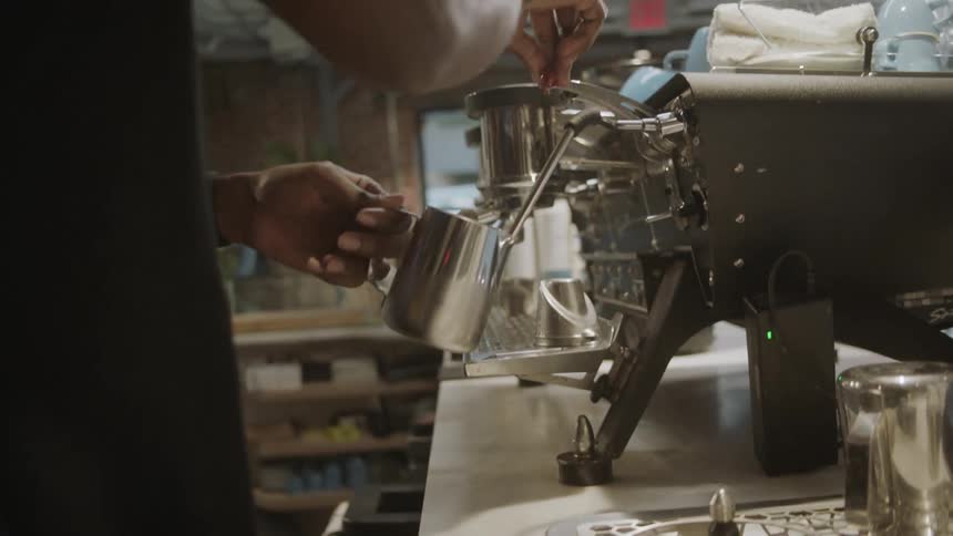 A man is using an coffee machine in the cafe