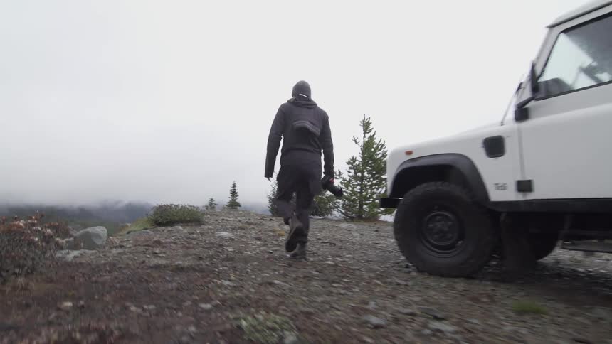 A man walks towards the cliff with a camera