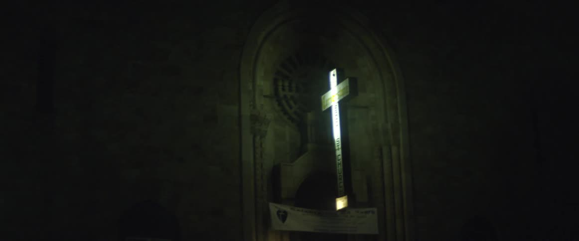 A cross is lit on the side of a building at night