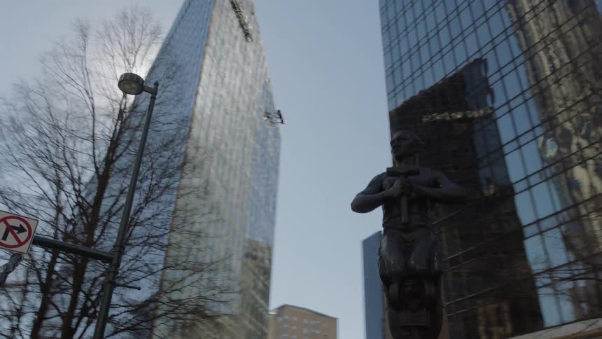 Modern sculpture in a plaza in front of tall skyscrapers in the city downtown at morning