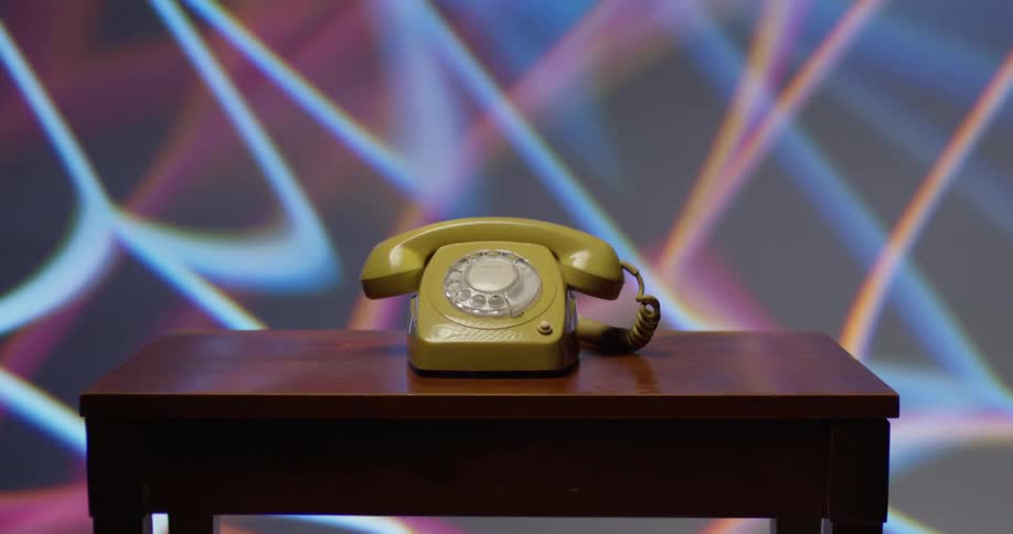 Vintage telephone sits on a table with colored lights behind it