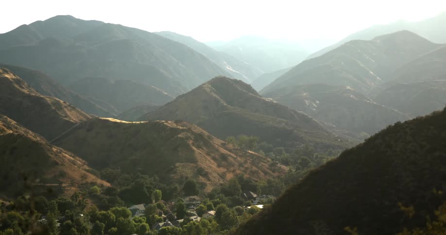 Homes nestled in a valley of rocky hills and mountains on a hazy day