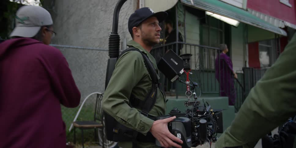 A man holds a camera as people walk around him