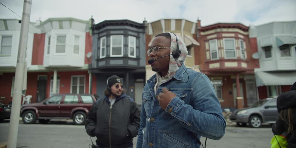 Two men are outside wearing headsets and talking