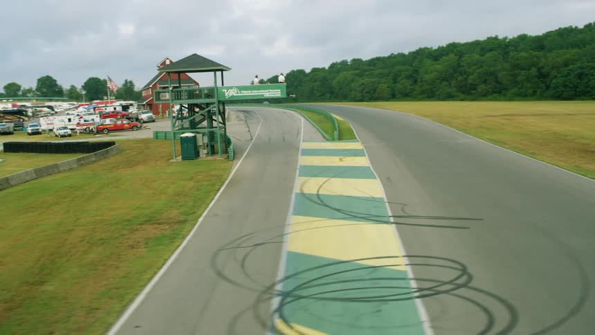 Multiple vehicles drive around an outdoor rural race track
