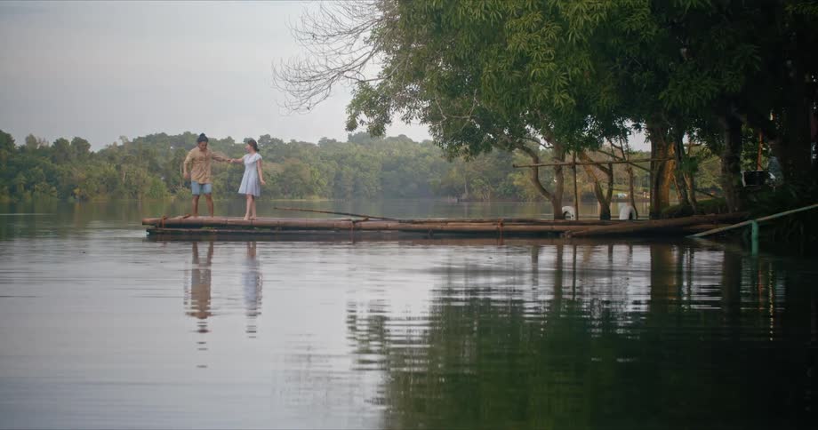 A couple is dancing on a dock on a lake