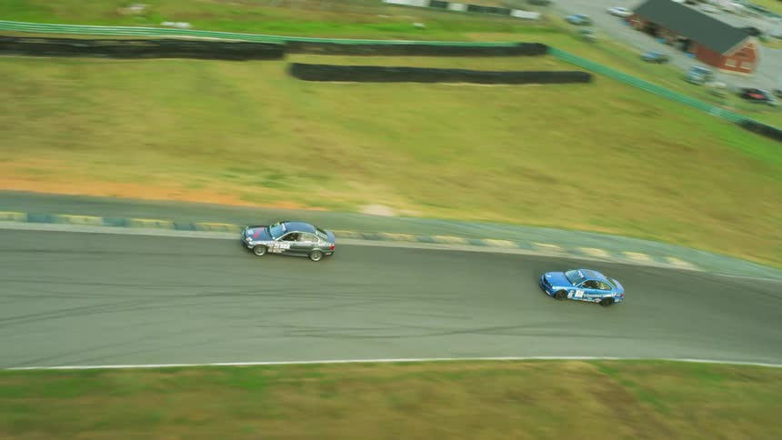 Vehicles racing on a racetrack with trees the sky and clouds in the background