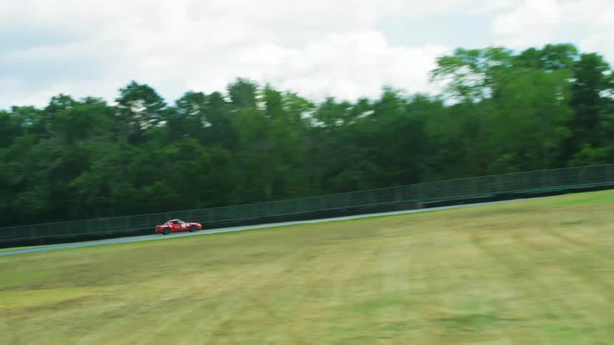 Race cars travel around a track with grass infield