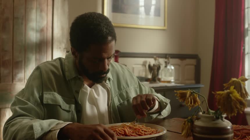 A man sits at home and eats spaghetti at the table