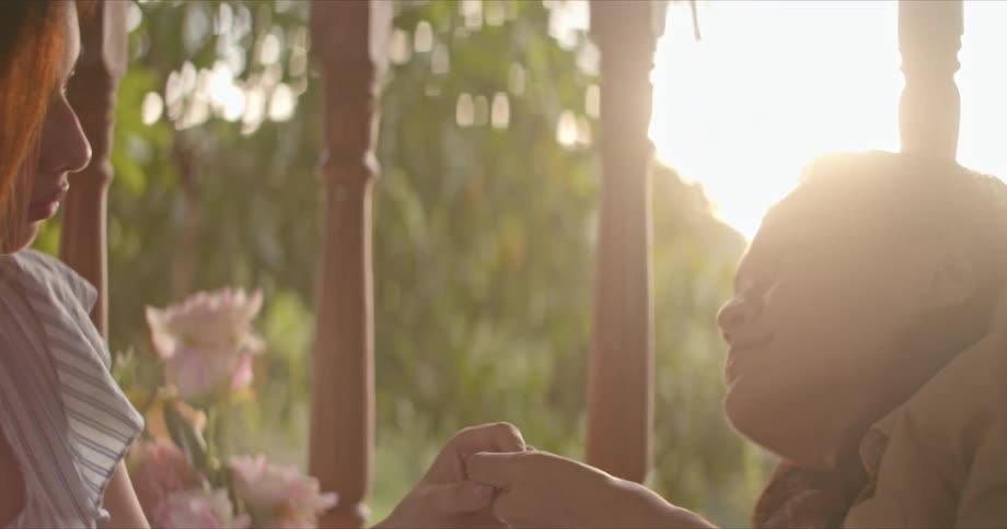 Young native american couple holding hands near the flowers in the porch at sunset