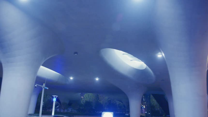 A large stylized bridge over a road in a metropolis at night