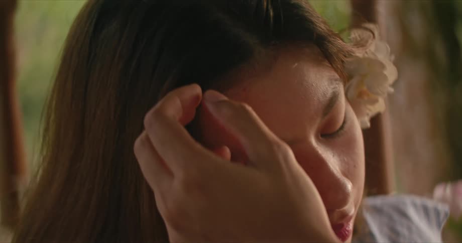 Man caresses the face of a young woman with his hand on the porch at sunset