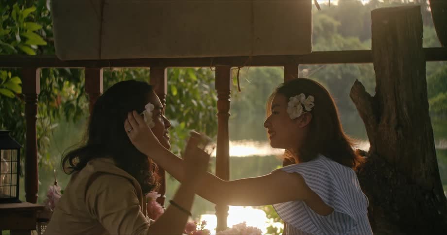 A woman attaches a flower to a womans head