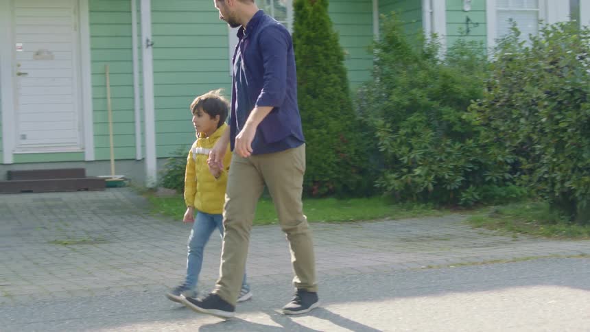Father and son walking away from house
