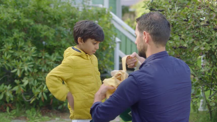 A father putting a backpack on a his son