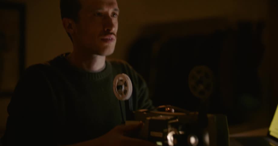 A man sets up his projector in a dark room