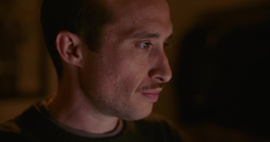 Man sits studying screen sighing and touching face