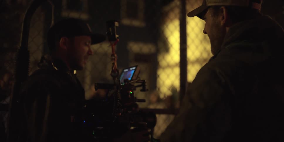 People are filming others behind a fence at night