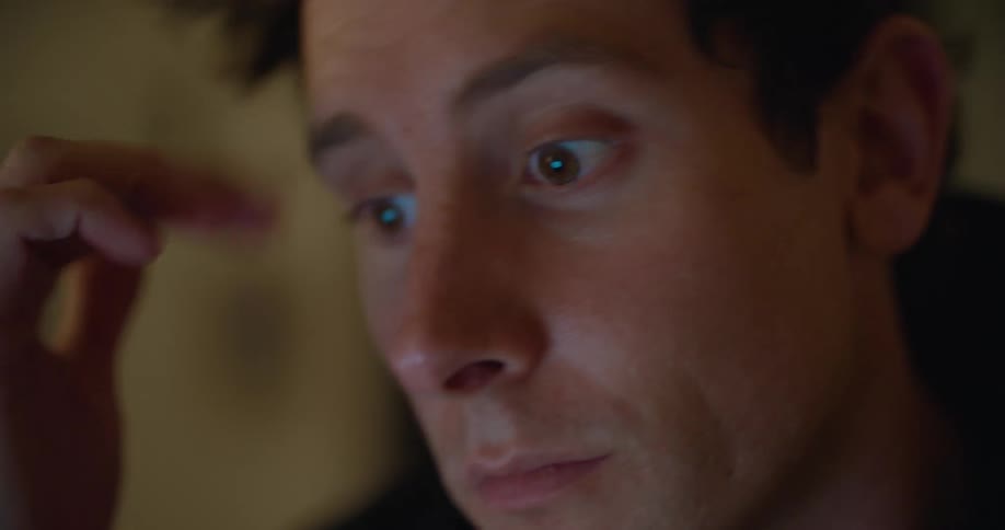 Man sits studying as his eyes reflect screen
