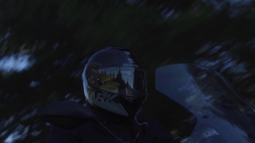 A rider drives a motorcycle on a sunny blue sky day
