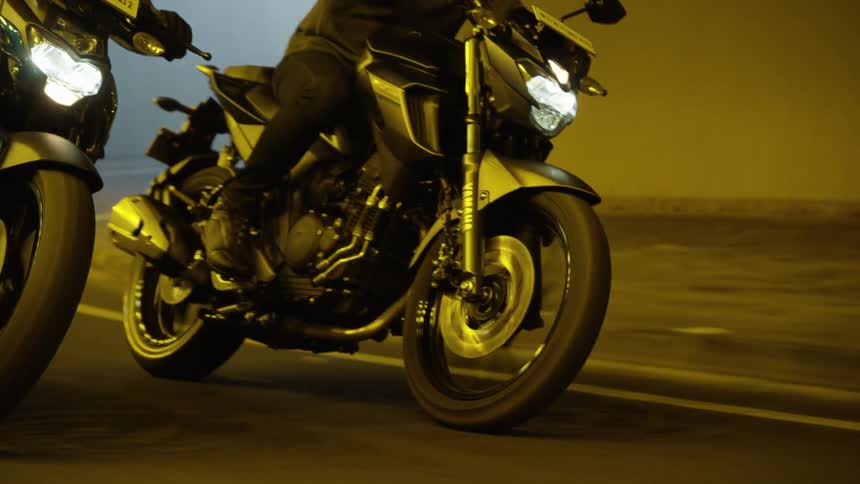 Two people ride their motorcycles through a tunnel