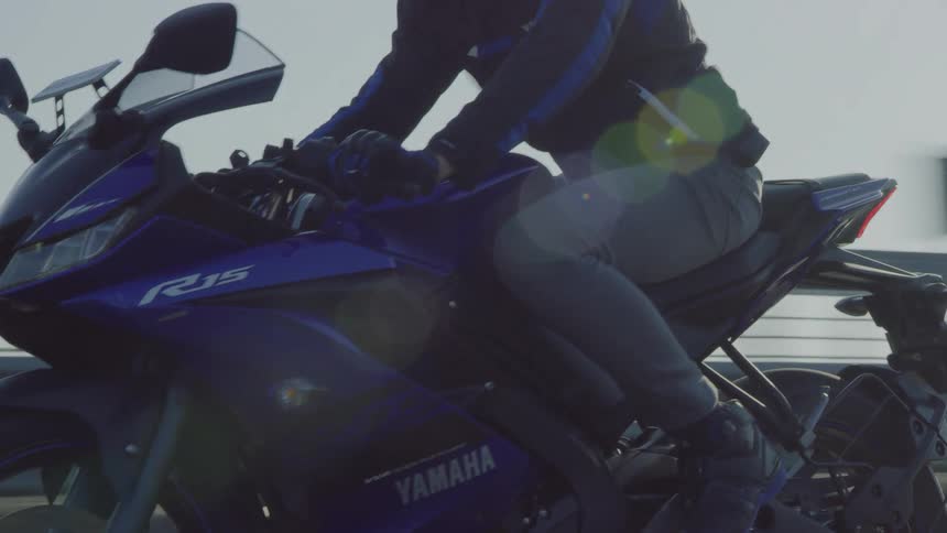 A person riding a motorcycle with a guardrail the sky and clouds in the background