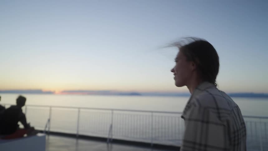 Woman walks past people sitting watching the sunrise on windy day