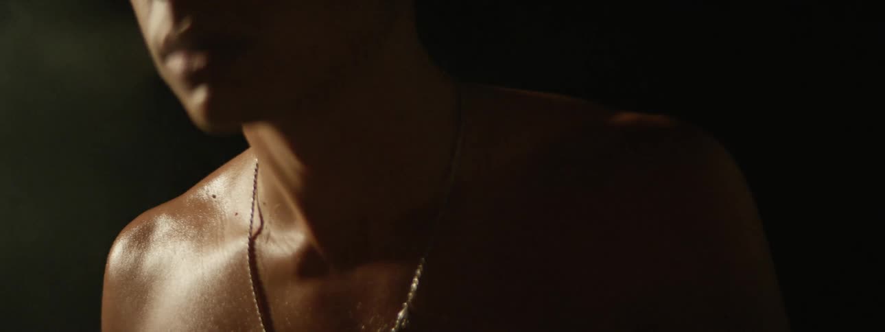 A shirtless man smokes a cigarette while covered in sweat
