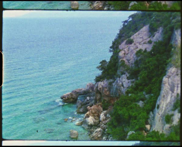 Rocks at the foot of the cliff next to the ocean at morning caught on vintage film