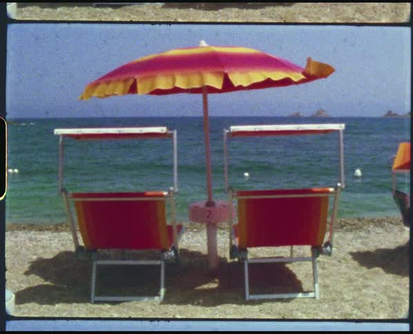 Chairs and an umbrella on a beach with the ocean the sky and clouds in the background