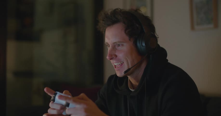 A man is playing a video game while talking into a headset