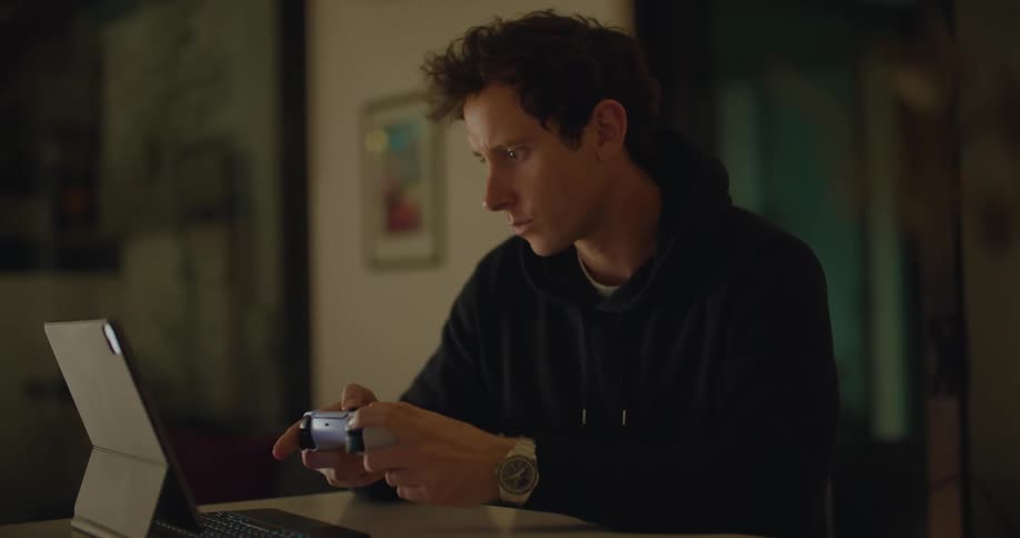 A man is playing videogames with a controller and tablet