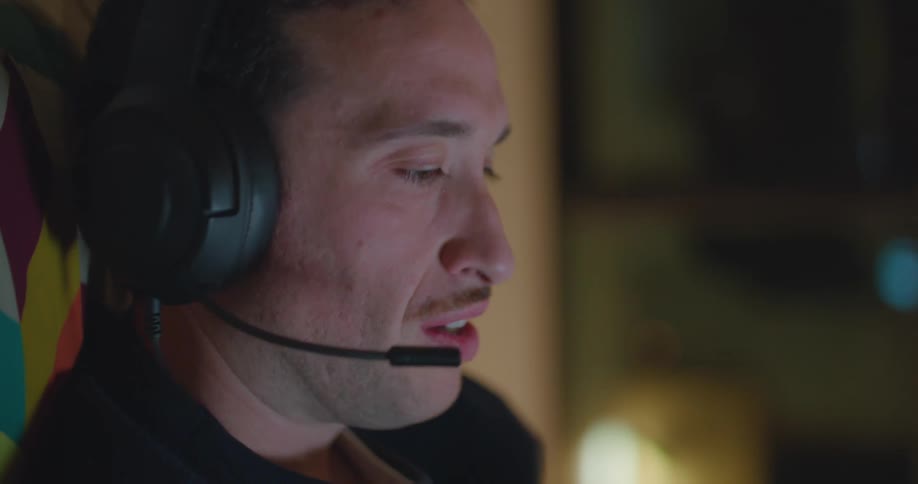 Man leans against cushion checking his wristwatch and the microphone on his headset as he talks