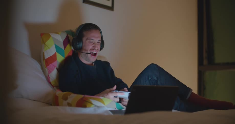 A man playing video games while laying on a bed