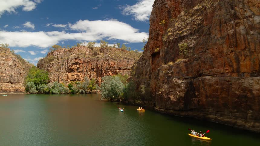People are kayaking in a canyon river