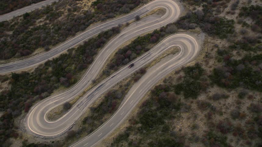 Aerial view of car driving on winding road in the field