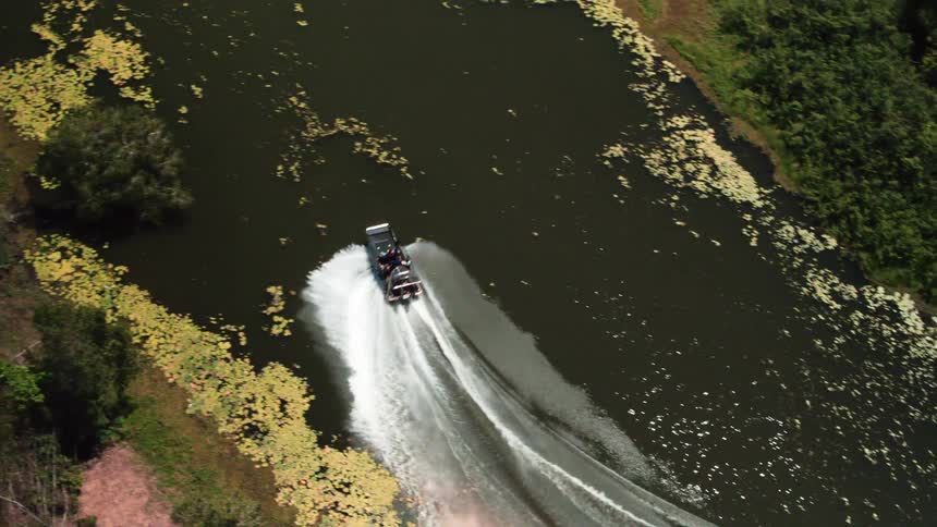 Boat speeds through river leaving wide foaming wake