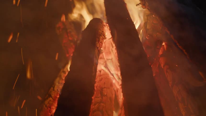 Flames rise as wood burns outside at night