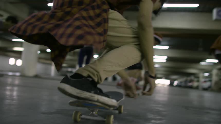 Four skateboarders jump and flip their boards while riding in a parking garage