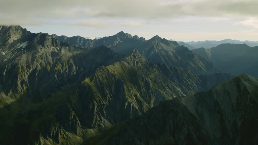 Fog settles over a mountain range covered in moss and algae