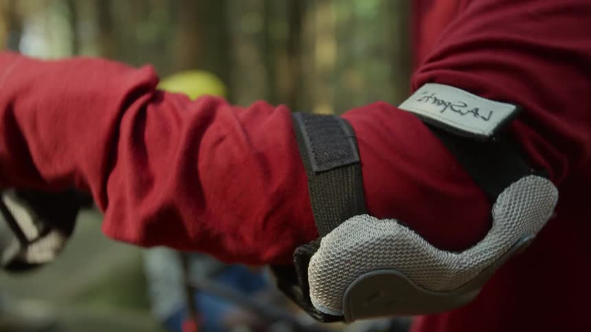 A man putting on arm pads outdoors