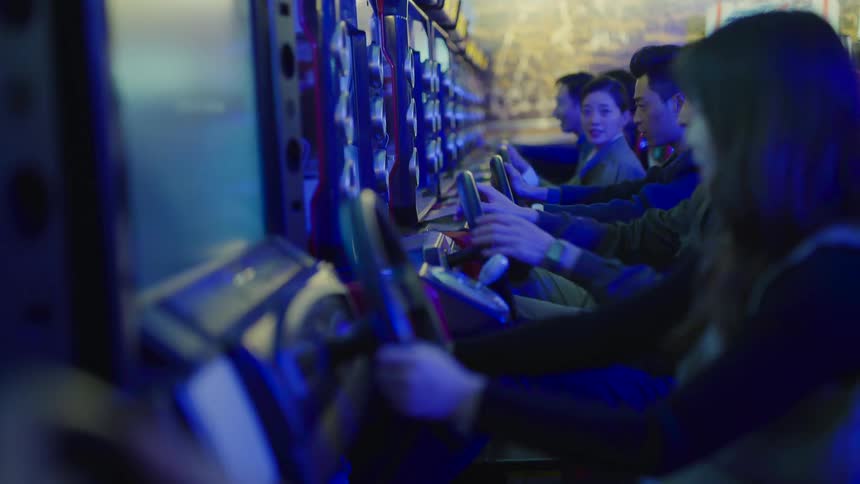 Group of friends playing racing video games inside an arcade