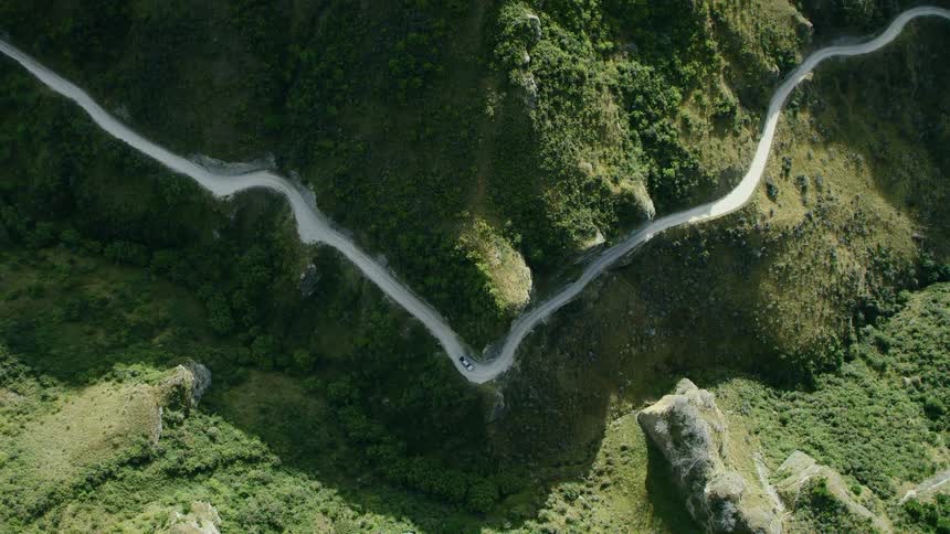 A vehicle drives on the winding mountain road