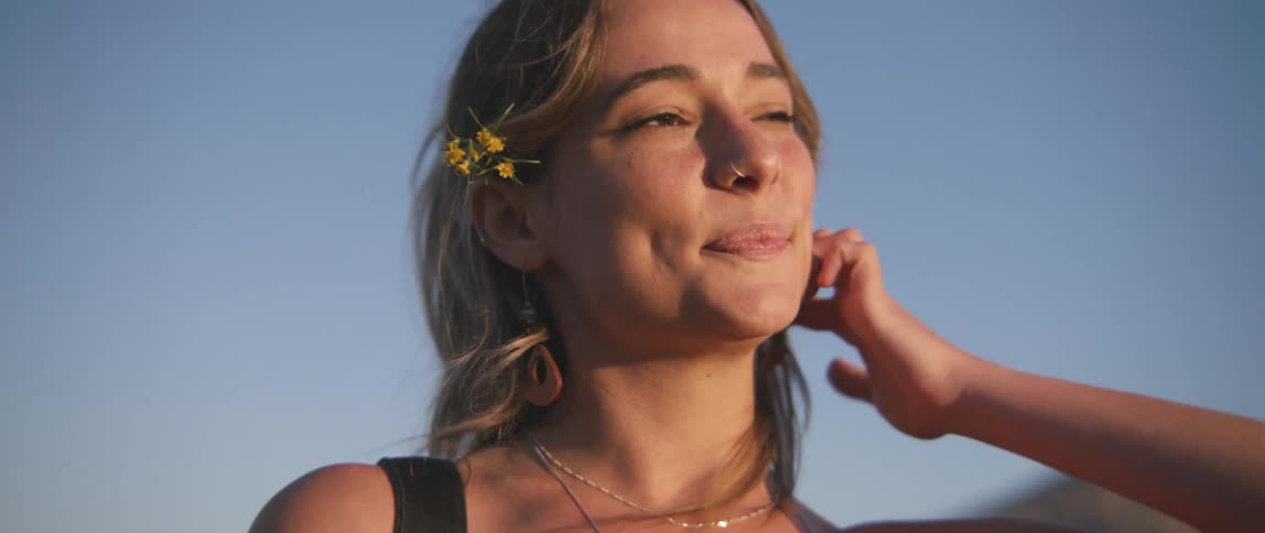 A woman tucks her hair behind her ear and leans her head back while closing her eyes