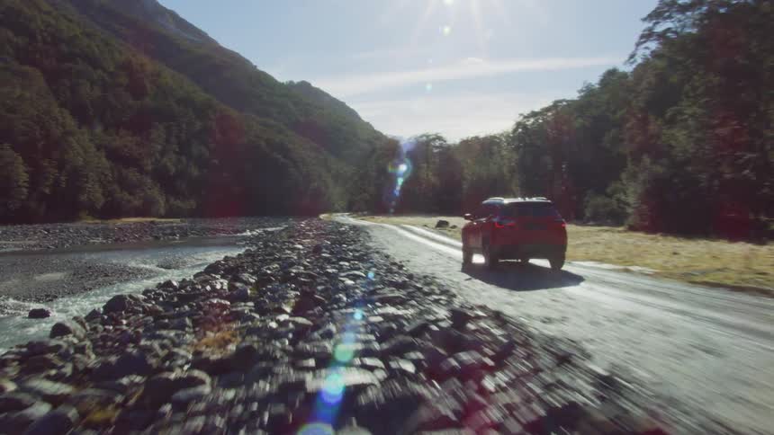A view of a suv driving outdoors on a dirt road