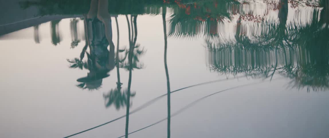 A womans reflection in a pool is displayed