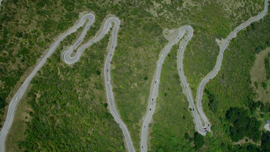 Traffic flows along long road that winds back and forth several times through sloping fields