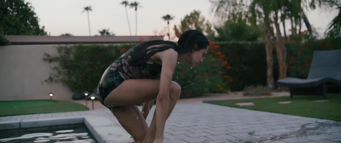 A woman laughs after getting out of her pool and squeezing water from her hair