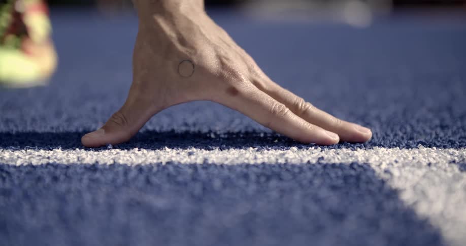A runner leans near the starting line