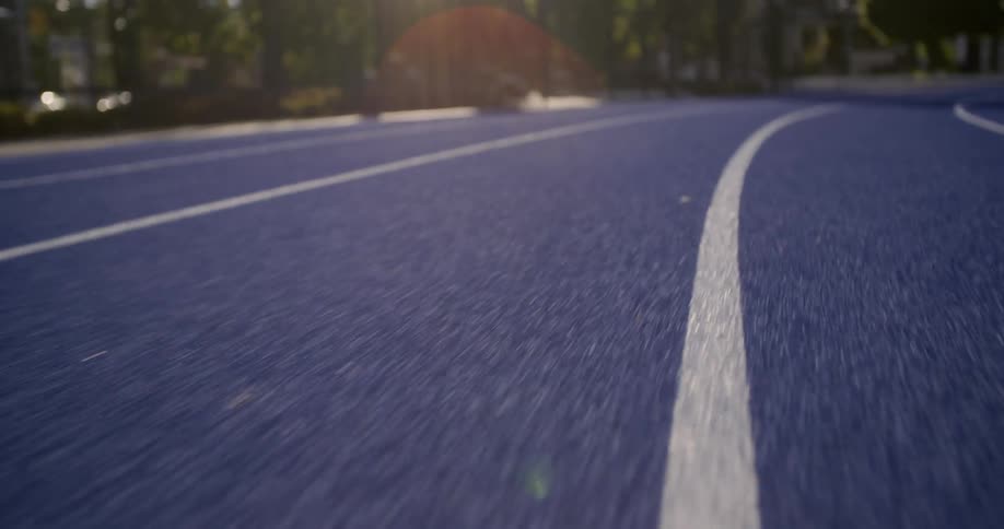 A person runs down a blue track